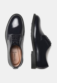 Navy leather dress shoes with a glossy finish, lace closure, a rounded toe, and a sturdy black sole. Interior features a beige lining.