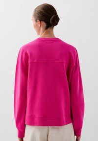 Fuchsia sweatshirt met lange mouwen, geribbelde halslijn en een ontspannen pasvorm. Beschikt over een horizontale naad over de rug en een zachte textuur.