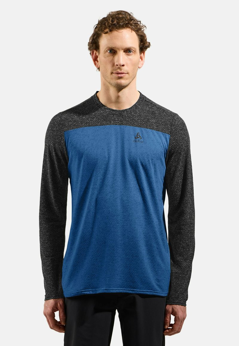 Langärmliges Hemd mit blauem Körper und schwarzen strukturierten Ärmeln. Das Material scheint leicht zu sein; Logo ist auf der Brust angebracht.