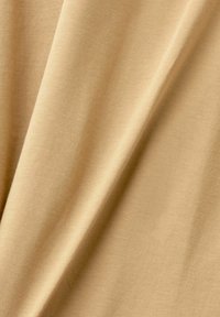 Tissu beige doux avec une texture lisse, présentant une apparence légère, légèrement extensible et un éclat subtil.