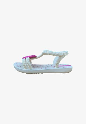 Sandalo bianco per bambini con cinturini intrecciati, pois rosa sulla suola e decorazione rosa a forma di cuore sul cinturino delle dita.