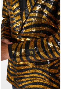 Schwarze und goldene Paillettenjacke mit gestreiftem Muster. Verfügt über einen Ein-Knopf-Verschluss, scharfe Revers und ein sichtbares Markenlabel am Ärmel.