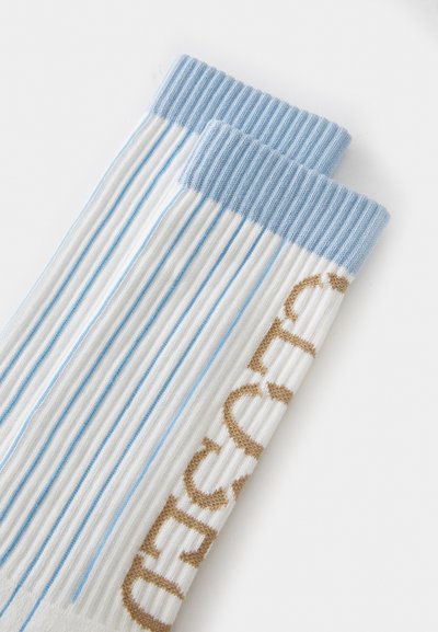 Calcetines de algodón con textura acanalada, que presentan un puño azul claro y finas rayas azules y blancas, junto con un detalle de texto bordado en dorado.
