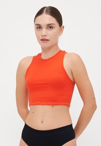 Orange cropped tank top with a high neckline and sleeveless design, paired with black high-waisted underwear. Smooth texture, simple lines.