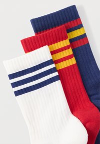Három pár térdig érő zokni: fehér tengerészkék csíkokkal, piros sárga csíkokkal, és sötétkék piros és sárga csíkokkal. Rugalmas bordás textúrájú.