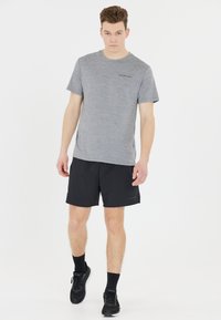 Graues Heather-T-Shirt mit kurzen Ärmeln und Rundhalsausschnitt, kombiniert mit schwarzen Shorts. Schwarze Sportschuhe und Socken vervollständigen das Outfit.