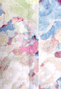 Tessuto morbido con un motivo astratto multicolore che presenta tonalità di rosa, blu, verde e crema, con una texture liscia e una sottile lucentezza.