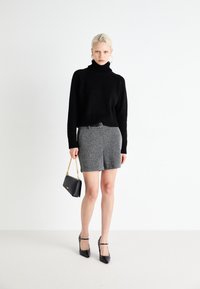 Juodas megztinis su aukšta apykakle, pilka tweed mini sijonas, juoda rankinė su grandinine dirželiu, juodos smailianosiai kulniukai su piktasiais.