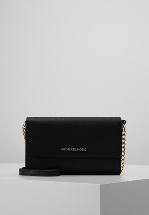 Zwarte leren Michael Kors clutch met textuur, voorzien van een gouden kettingbandje en een goudkleurig reliëflogo op de voorklep, tentoongesteld op een witte ondergrond.