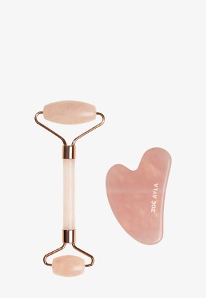 Rouleau facial en quartz rose avec deux rouleaux de tailles différentes et un outil gua sha assorti gravé du nom de la marque sur fond blanc.
