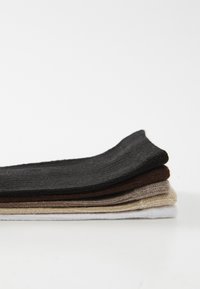 Five pairs of socks stacked horizontally: black, dark brown, light brown, beige, and white. Each pair has a ribbed texture.