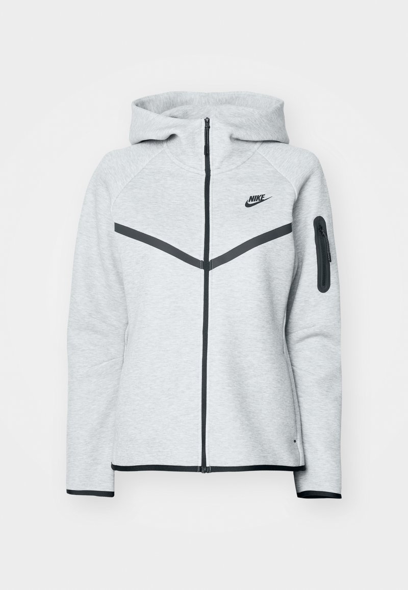 Grå lynlås-hoodie med hætte og sorte accenter, der har et diagonalt design på forsiden, Nike-logo og en lynlåslomme på ærmet.