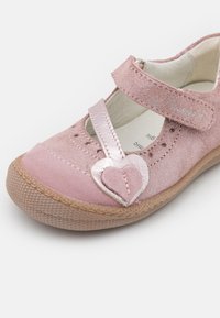 Różowy dziecięcy but z zapięciem na rzep, ozdobiony kształtem serca, z teksturowaną gumową podeszwą, zaprojektowany z myślą o komforcie i łatwości zakupu.