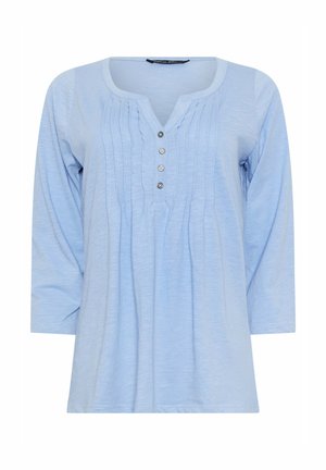 Lyseblå langærmet bluse med rund halsudskæring, forreste læg og fire sølvknapper ned langs midten.