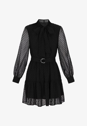 Rochie neagră cu mâneci lungi, din material transparent, textură cu buline, guler cu fundiță, talie strânsă cu o cataramă argintie și fusta cu volane suprapuse.