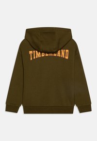 Olivově zelená mikina s kapucí, na které je na zadní straně velký zakřivený nápis "TIMBERLAND" v oranžové barvě. Má kapuci a žebrované manžety. Měkká textilie.