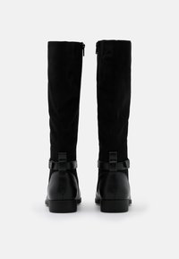 Bottes noires montantes jusqu'aux genoux au design élégant, fabriquées en matériau doux avec des accents en cuir, un bout arrondi et une fermeture éclair à l'arrière.