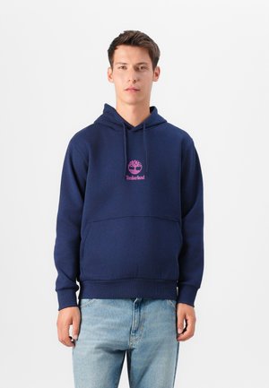 Navy blue hoodie with a front kangaroo pocket, ribbed cuffs, and waistband. Features a pink Timberland logo on the chest. Cotton blend material.