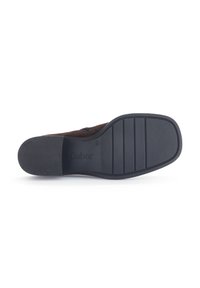 Suela de zapato de ante marrón con una parte inferior de goma negra texturizada. Presenta un logotipo y surcos horizontales para mejorar el agarre.