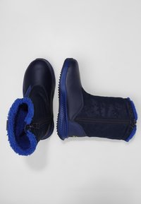 Námořnické modré zimní boty s hladkým svrškem a strukturovaným textilním zvrškem, s zipovým uzávěrem a chlupatým modrým podšívem. Gumená podrážka pro lepší uchopení.