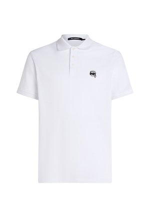 Valge polo-särk, millel on krae, kolm nuppu ja väike must logo vasakul rinnal. Valmistatud hingavast kangast lühikeste varrukatega.