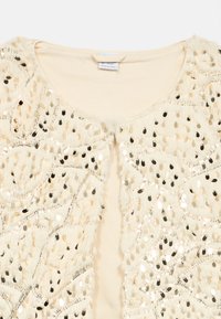 Κρεμ ύφασμα με λαμπερά χρυσά και μαύρα παγιέτα σε σχέδιο φύλλου, διακοσμημένα στο ντεκολτέ και τους ώμους ενός ενδυματος.