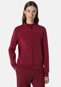 Bordeauxfarbener Reißverschluss-Pullover mit hohem Kragen, langen Ärmeln und Seitentaschen. Glattes Material mit taillierter Passform und dezenten Nähdetails.