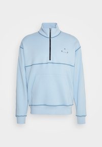 Světle modrý, pulovr s čtvrtinovým zipem vyrobený z měkké tkaniny. Obsahuje klokaní kapsu, černý zip a monochromatické logo a textové akcenty.