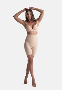 Ropa interior beige con un bralette de tirantes finos y pantalones cortos de talle alto. Textura suave, diseño sin costuras y longitud hasta la mitad del muslo.
