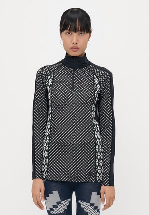 Svart langermet topp med høy krage, med et geometrisk mønster i hvitt, glidelås foran og tettsittende design.