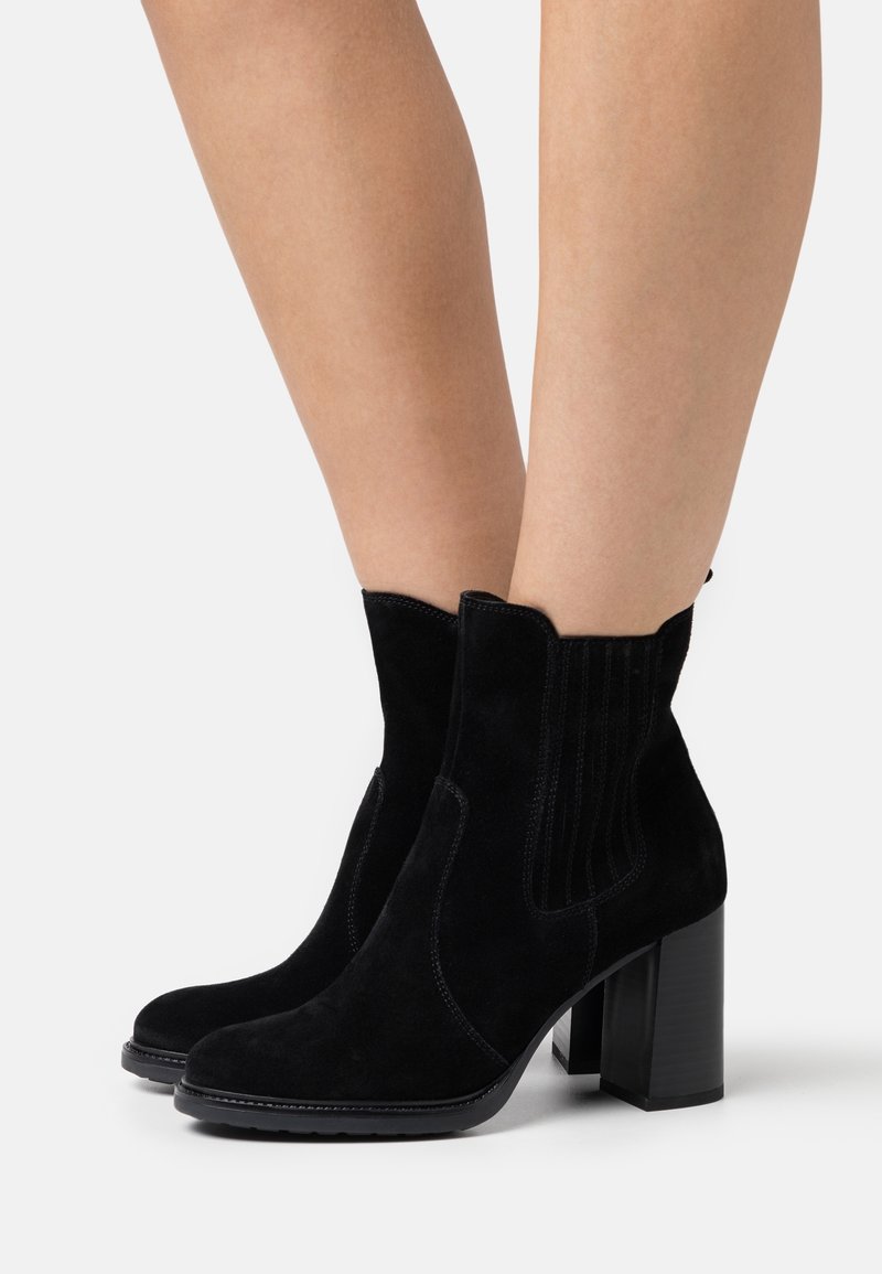 Svarta mocka ankelstövlar med rund tå, elastiska sidopaneler och en kraftig blockklack. Designen har vertikala sömnadsdetaljer.