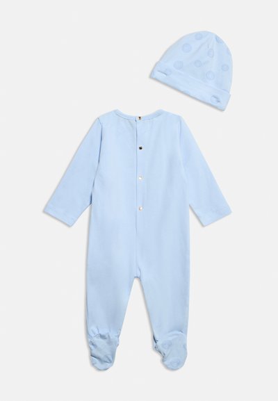 Φωτεινό γαλάζιο βρεφικό φορμάκι με μακριά μανίκια και κουμπιά στο πίσω μέρος, συνδυασμένο με καπέλο που έχει διακριτικά κυκλικά μοτίβα.