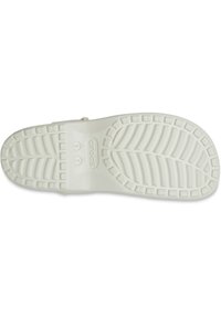 Witte rubberen sandaal met een gekarteld loopvlak, voorzien van een zigzagpatroon en diepe groeven voor grip. Het merkembleem is in de tussenzool gedrukt.