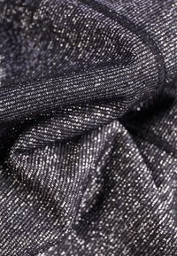 Tessuto nero con fili d'argento lucidi, caratterizzato da una trama strutturata. La superficie ha una leggera lucentezza, creando un effetto scintillante.