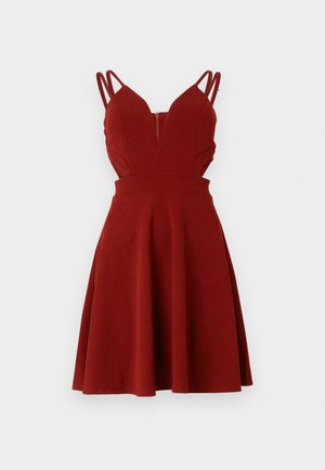 Red sleeveless dress with a fitted top, deep V-neck, and flared skirt. Features thin straps and a zipper at the back. Smooth fabric texture.
