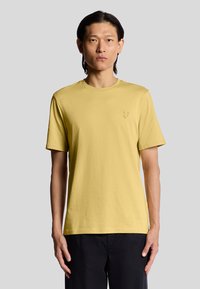 Kortærmet gul t-shirt i blødt bomuld. Den har en rund halsudskæring og et lille broderet logo på brystet.