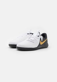 Witte sport schoenen met zwarte en gouden accenten, voorzien van een textuur en een prominente Nike swoosh logo aan de zijkant.