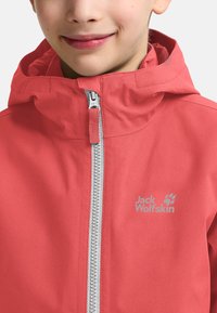 Giacca impermeabile corallo con cerniera frontale, cappuccio regolabile e logo "Jack Wolfskin". Il tessuto ha una superficie liscia e un design casual.