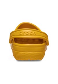Gele rubberen klompen met een achterste band, voorzien van een gestructureerd oppervlak, afvoergaten en een reliëf logo op de band.