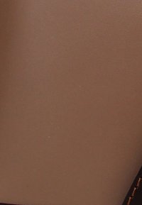 Bruine lederen textuur met een glad oppervlak; heeft donkere stiksels langs een rand. Geen opvallende patronen of hardware zichtbaar.