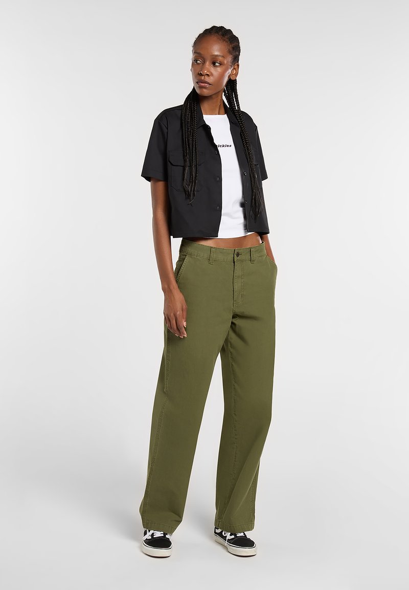 Green wide-leg pants with a classic fit, made of durable fabric. Paired with a cropped black button-up shirt and white graphic t-shirt.