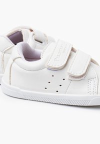 Białe skórzane dziecięce buty z dwoma paskami na rzep, perforowanymi detalami po bokach oraz teksturowaną gumową podeszwą. Miękka wewnętrzna wyściółka.