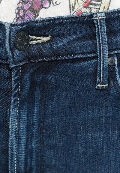 Donkerblauwe spijkerbroek met een rits en knoopsluiting, voorzien van contrasterende stikdetails en een klein label bij de tailleband.