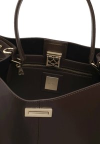 Brązowa skórzana torebka z złotymi akcentami. Posiada kieszonkę na zamek oraz dekoracyjny zamek. Wnętrze zawiera metkę z nazwą marki.