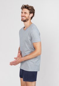 Grijze katoenen t-shirt met korte mouwen en een ronde hals, gecombineerd met marineblauwe shorts. De stof lijkt zacht met een gladde textuur.