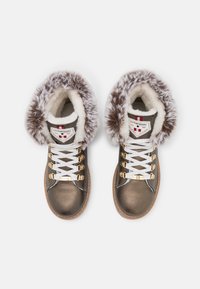Botas de imitación de cuero marrón con un cuello de pelo sintético blanco, cordones blancos, herrajes dorados y una suela de goma marrón. Marcadas con un parche de logo.