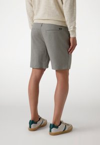 Gray shorts made of fabric, featuring a waistband, two back pockets, and a smooth texture. Paired with casual sneakers in light colors.