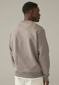 Sudadera gris con un diseño sencillo, presenta un cuello redondo y puños acanalados. Tejido suave y texturizado con un ajuste relajado.