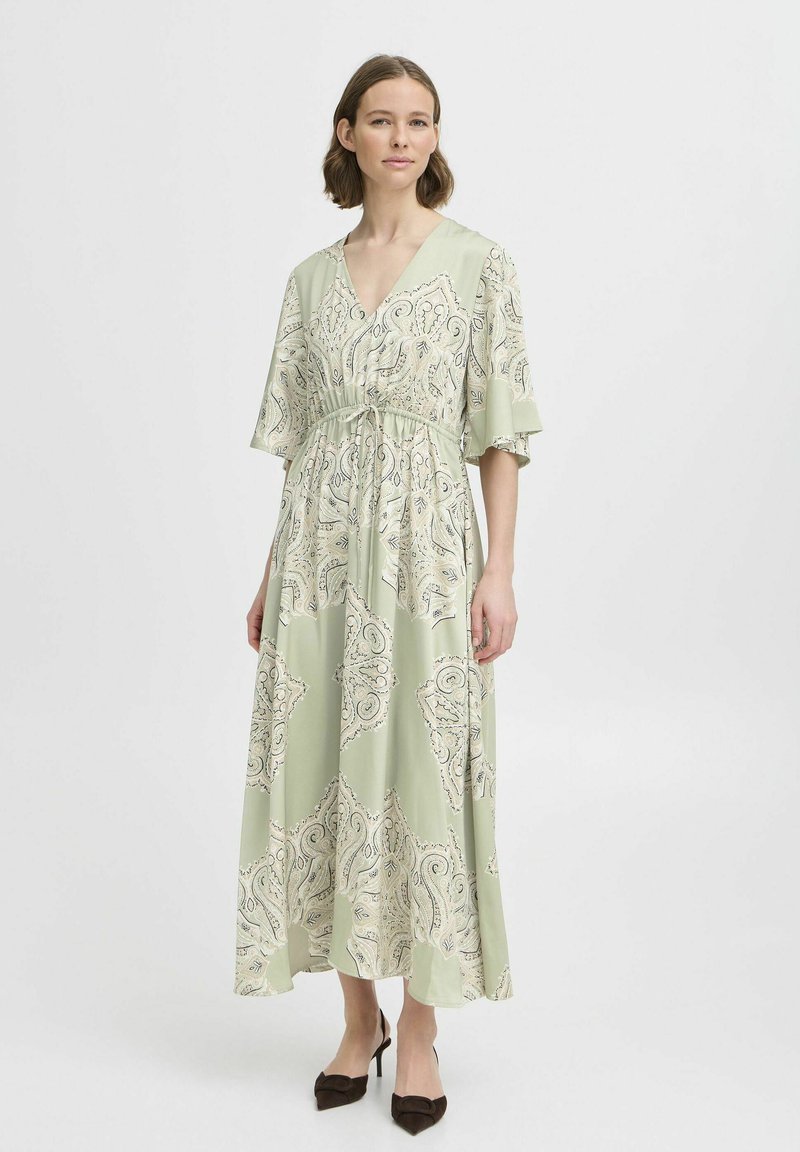 Rochie lungă verde deschis, cu decolteu în V, mâneci flutură și un model paisley în crem și albastru. Detaliu cu talie elastică, țesătură netedă.