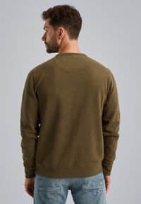 Oliwkowa bluza z długim rękawem, okrągłym dekoltem oraz prążkowanymi mankietami i dolnym wykończeniem. Miękka tekstura, prosty design oraz okrągły detal z tyłu.